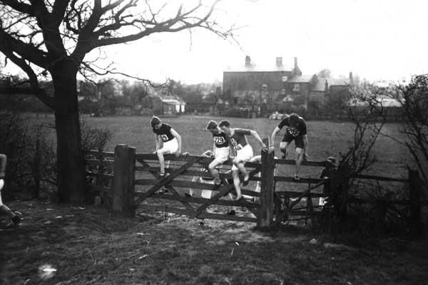 March 1913: Competitors in the English National Cross Country Championships climbing over a gate on the route