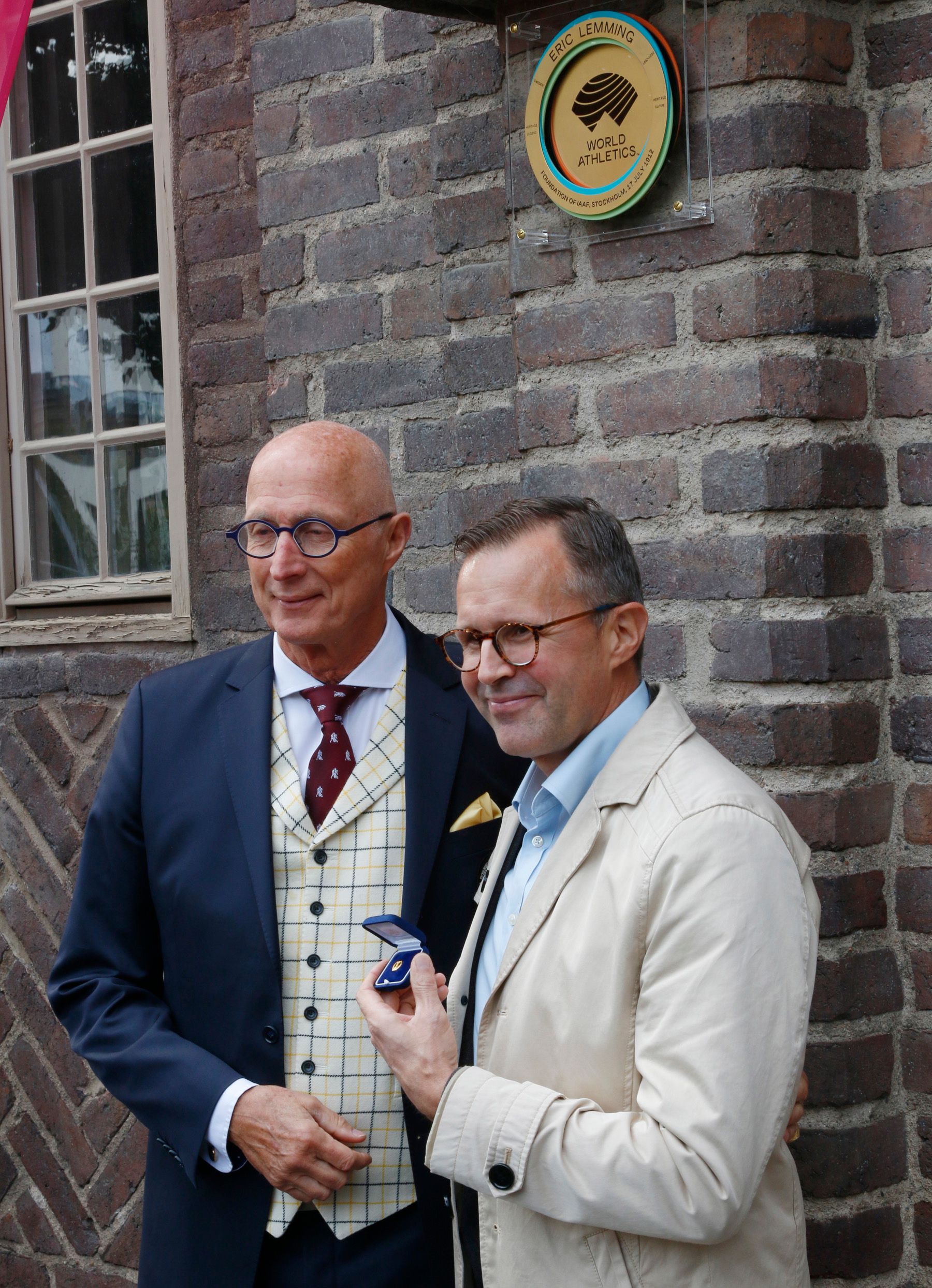Rajne Soderberg (left) with Fredrik Lemming, beneath plaque honouring Eric Lemming and the foundation of IAAF