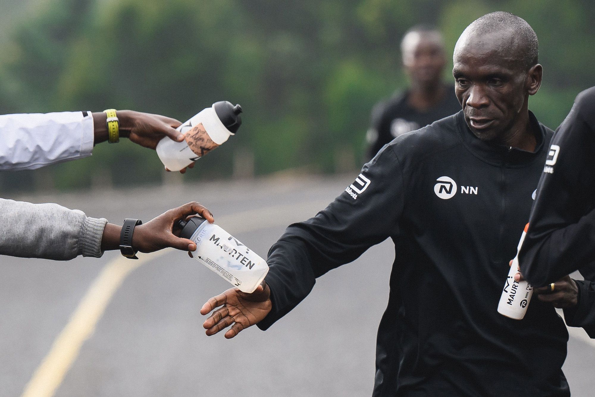 Eliug Kipchoge takes a drink on his training run