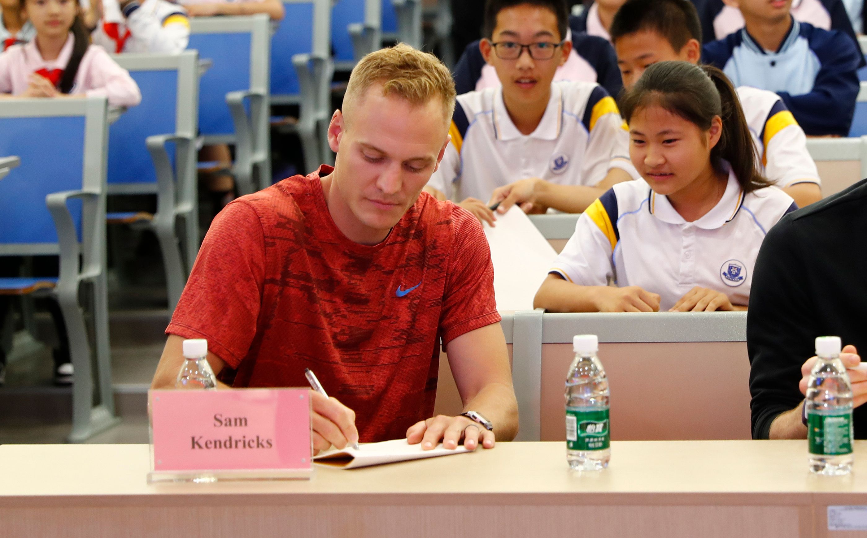 Sam Kendricks writes a note during a school visit in Xiamen