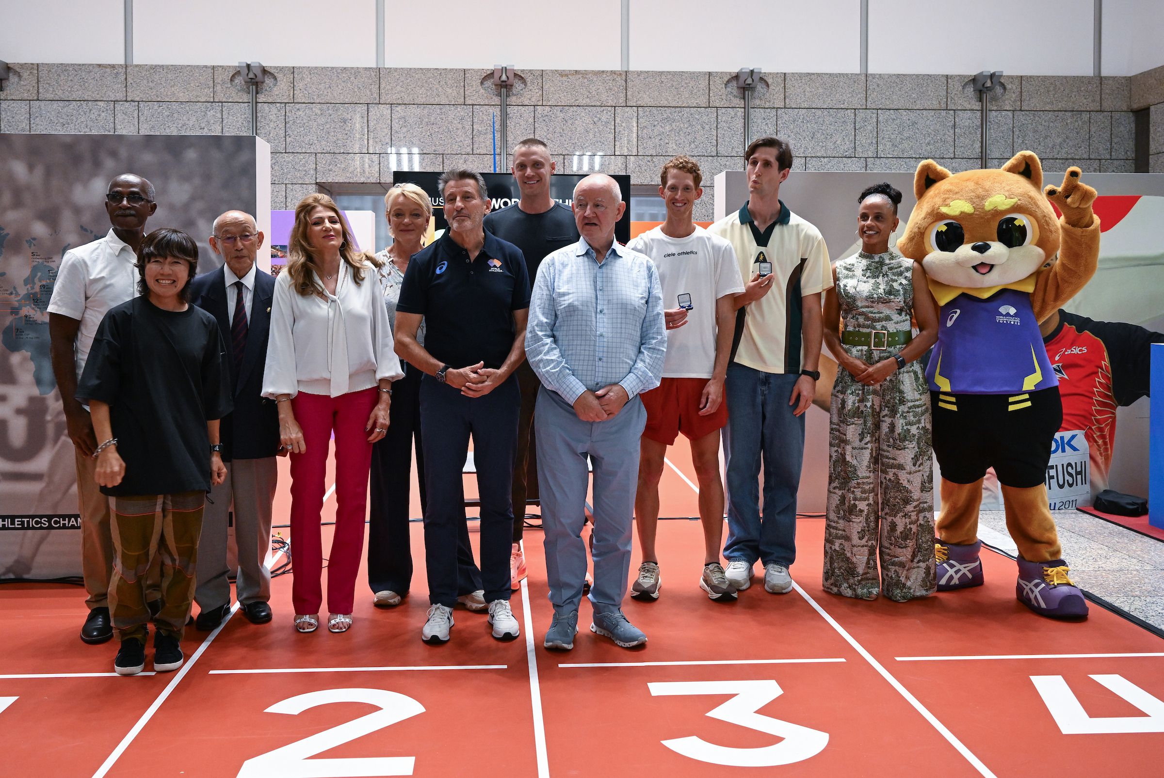 The donors with Sebastian Coe, Michael Burke and WCH Tokyo 25 mascot Riku One at the MOWA donation ceremony
